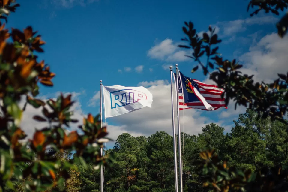 Flags on tall flagpoles with RTP logo and North Carolina flag at Research Triangle Park.